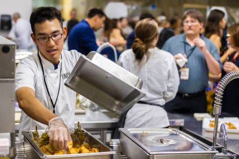 UNLV hospitality student Jay Chang, left, refreshes food trays at UNLVino on Saturday, May 7, 2 ...