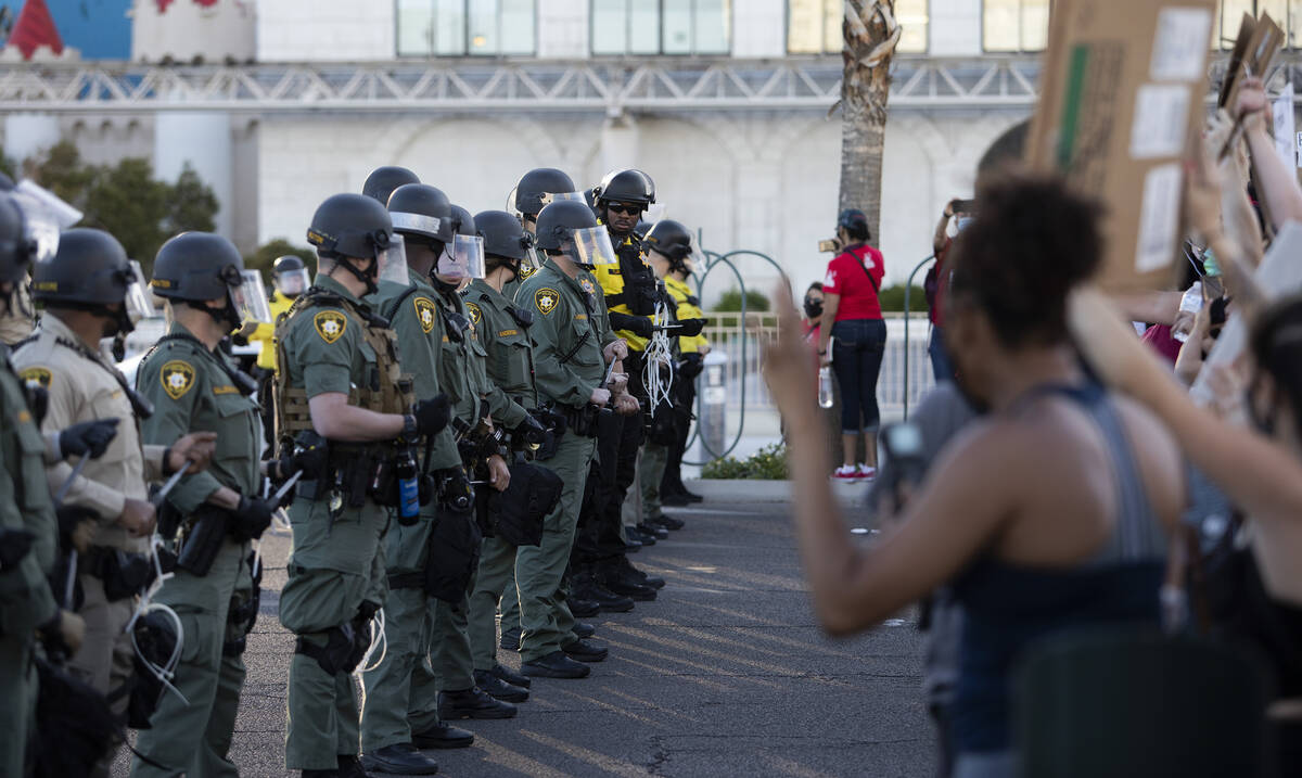 Police don riot gear and form a line outside Excalibur as protesters make way down Las Vegas Bo ...