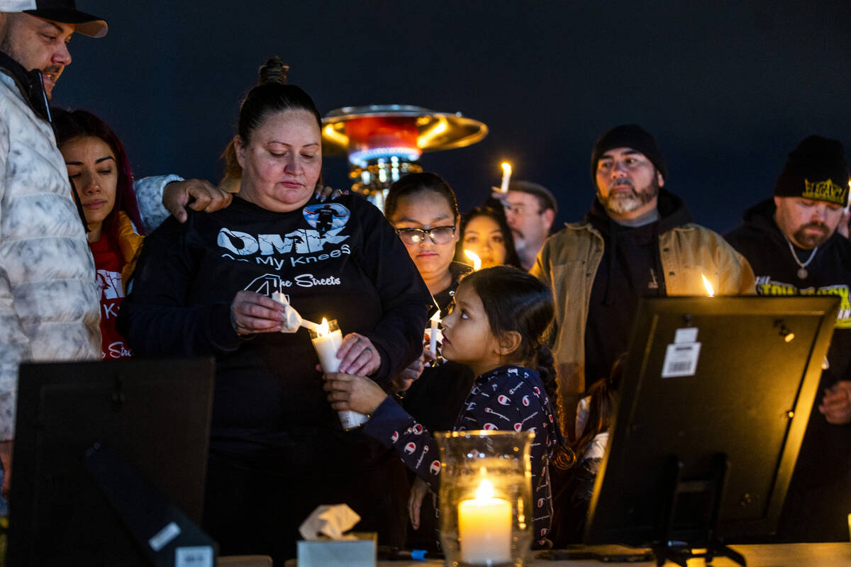 Wife Angela Dominguez, center, lights a candle for a child as they and others honor Jonet Domin ...