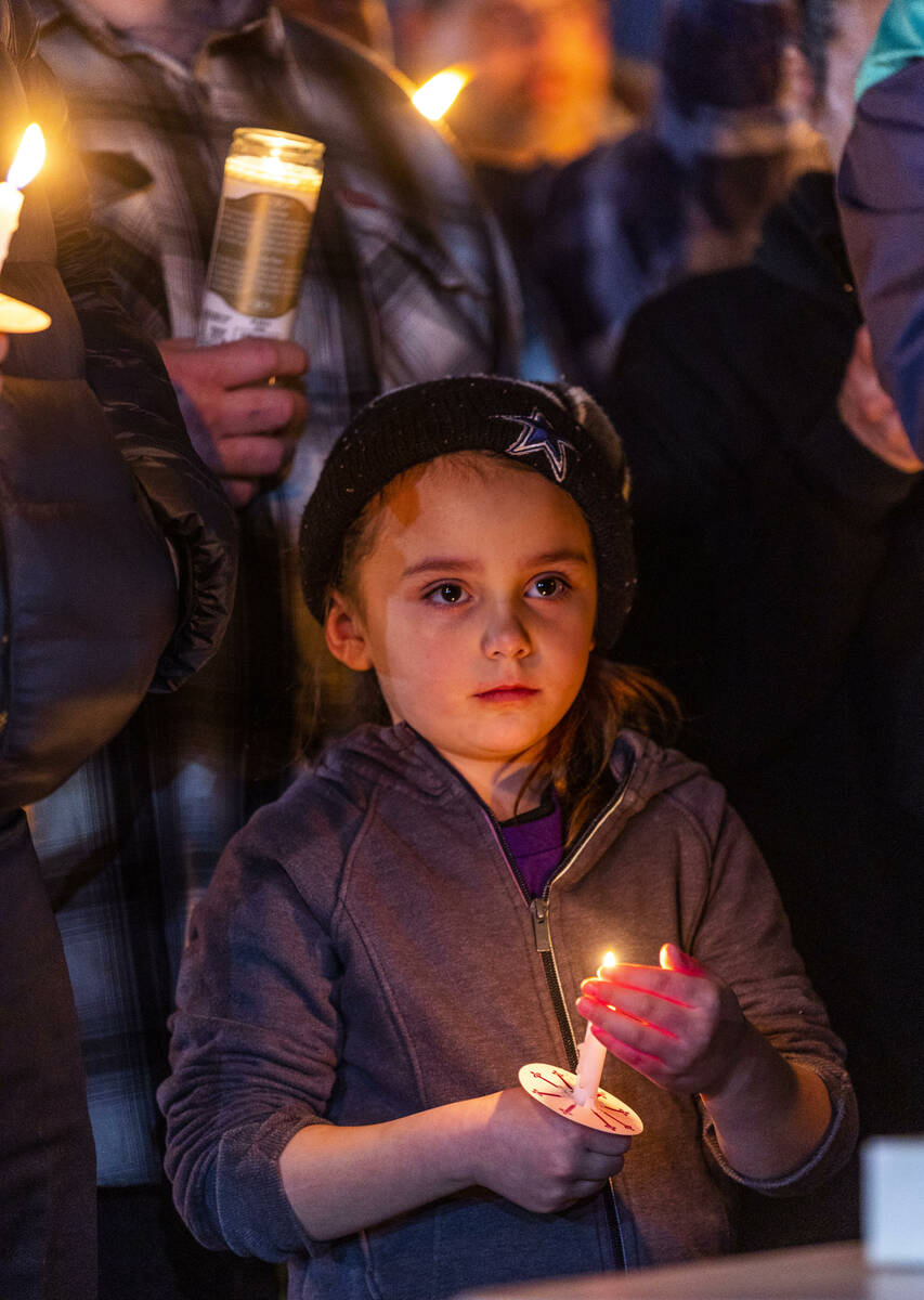 A child holds a candle as they and others honor Jonet Dominguez during a candlelight vigil at A ...