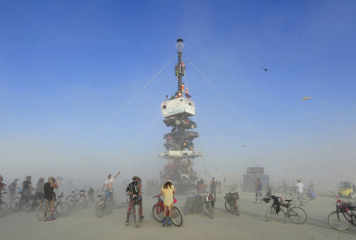 Burners climb onto an art installation titled, "Night of the Climb," at Burning Man, near Gerla ...