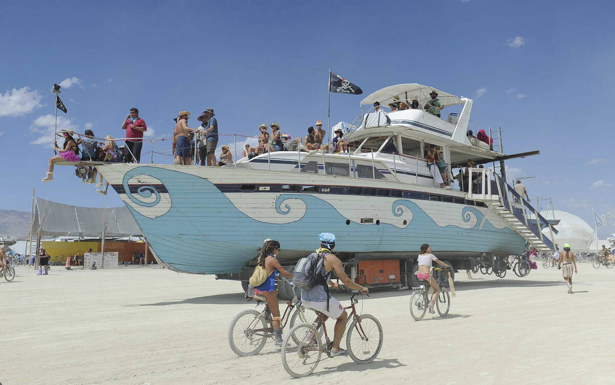 An old wooden yacht art car rolls through the playa at Burning Man on the Black Rock Desert nea ...