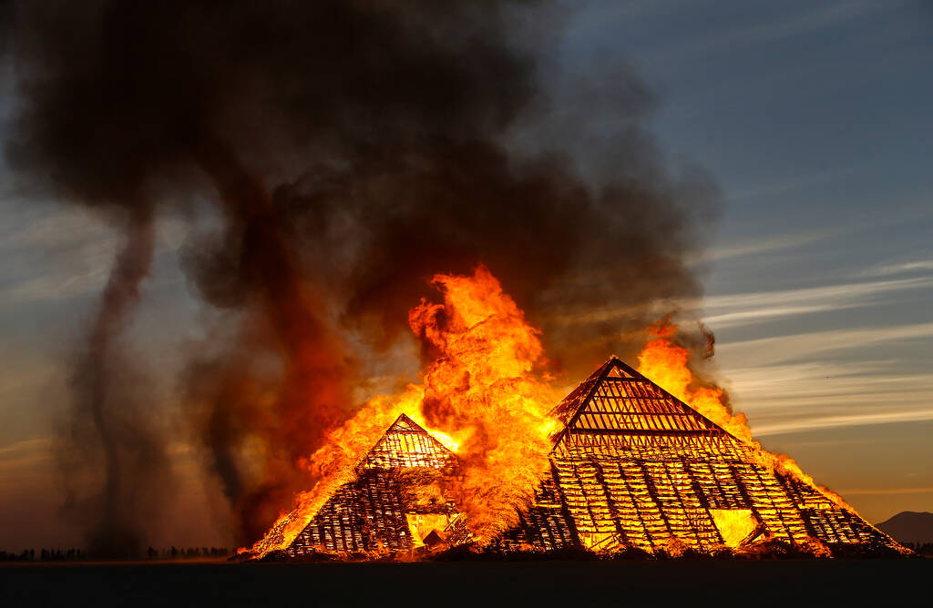 Dust devils kick up as the Catacomb of Veils art installation burns at sunrise during Burning M ...