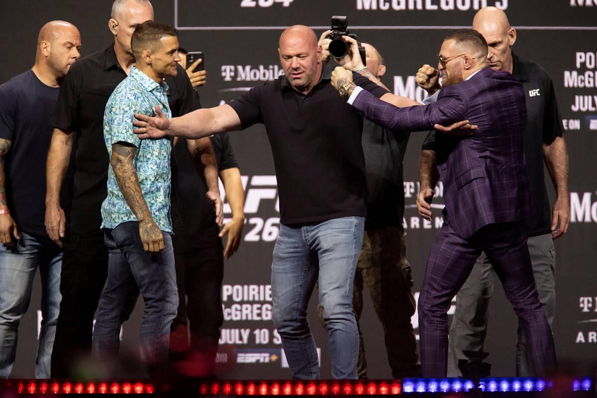 Dana White, center, stands between Dustin Poirier, left, and Conor McGregor during their face o ...