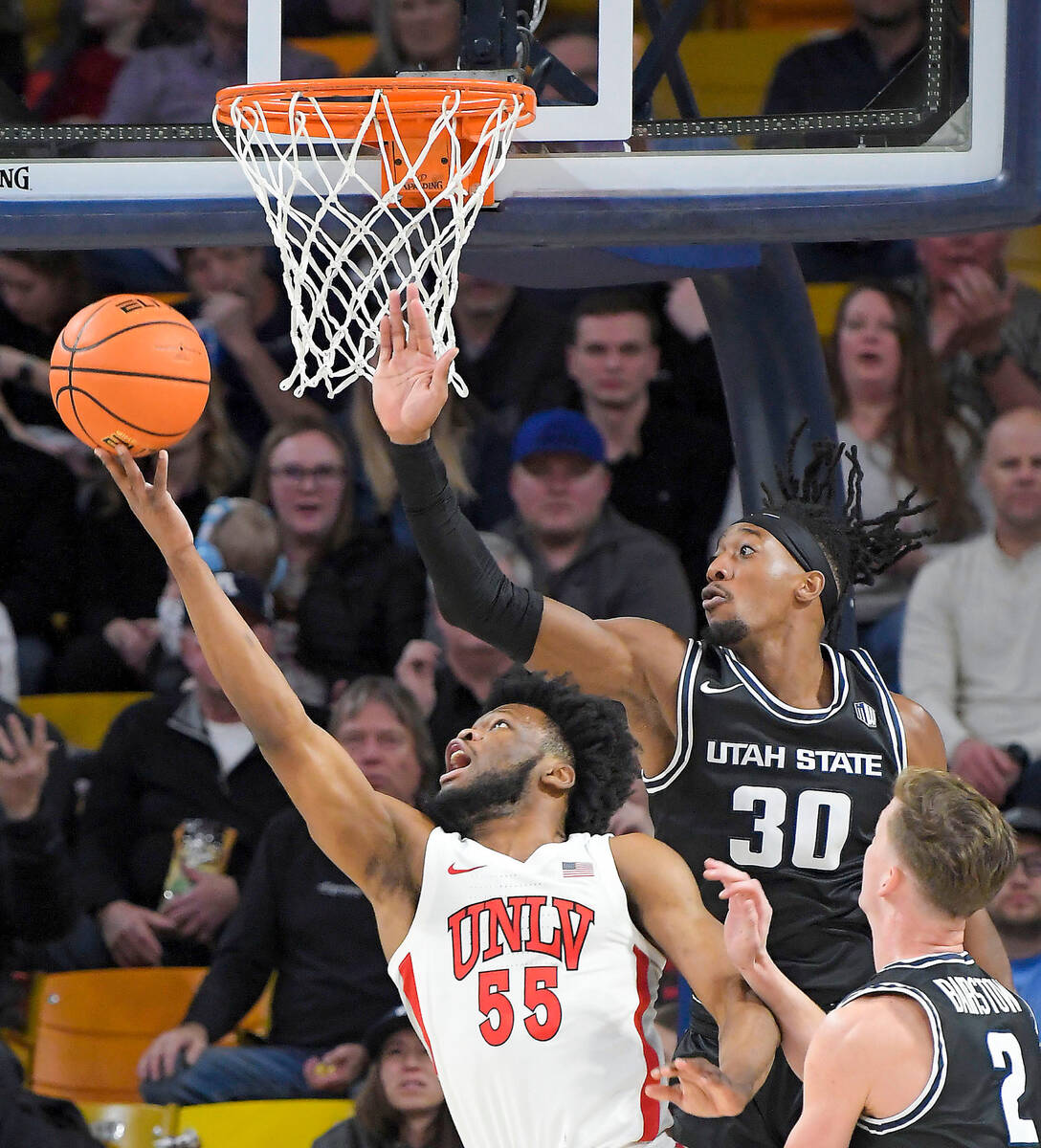 UNLV guard EJ Harkless (55) shoots the ball as Utah State forward Dan Akin (30) and guard Sean ...