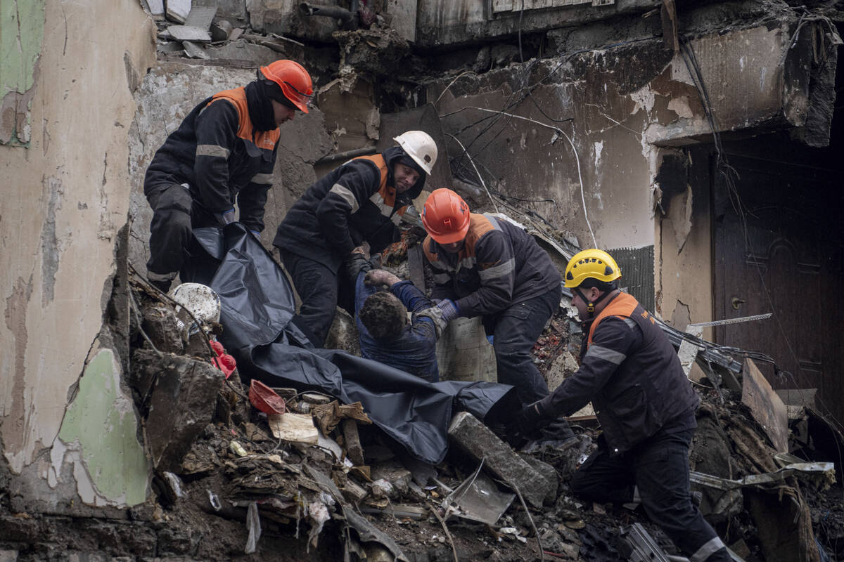Rescue workers transfer the body of a man killed in a Russian missile strike on an apartment bu ...