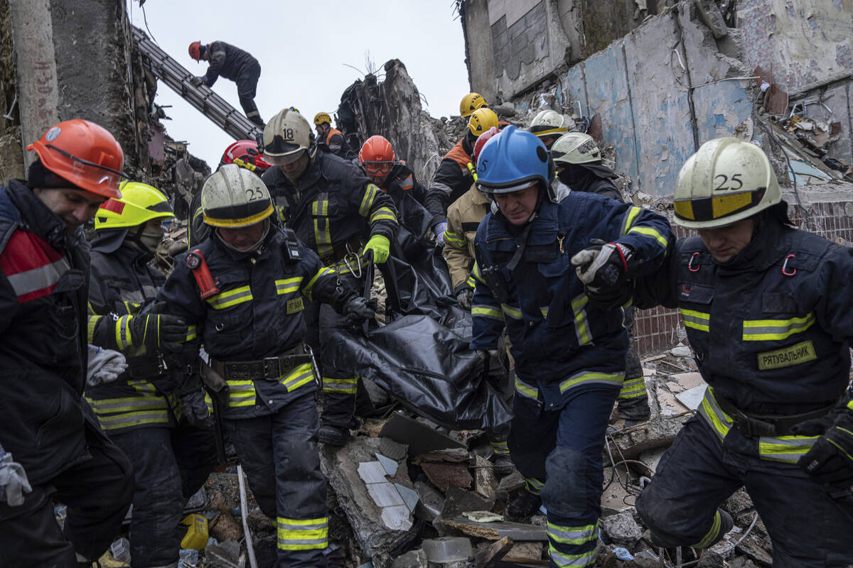 Rescue workers carry the body of a man who was killed in a Russian missile strike on an apartme ...