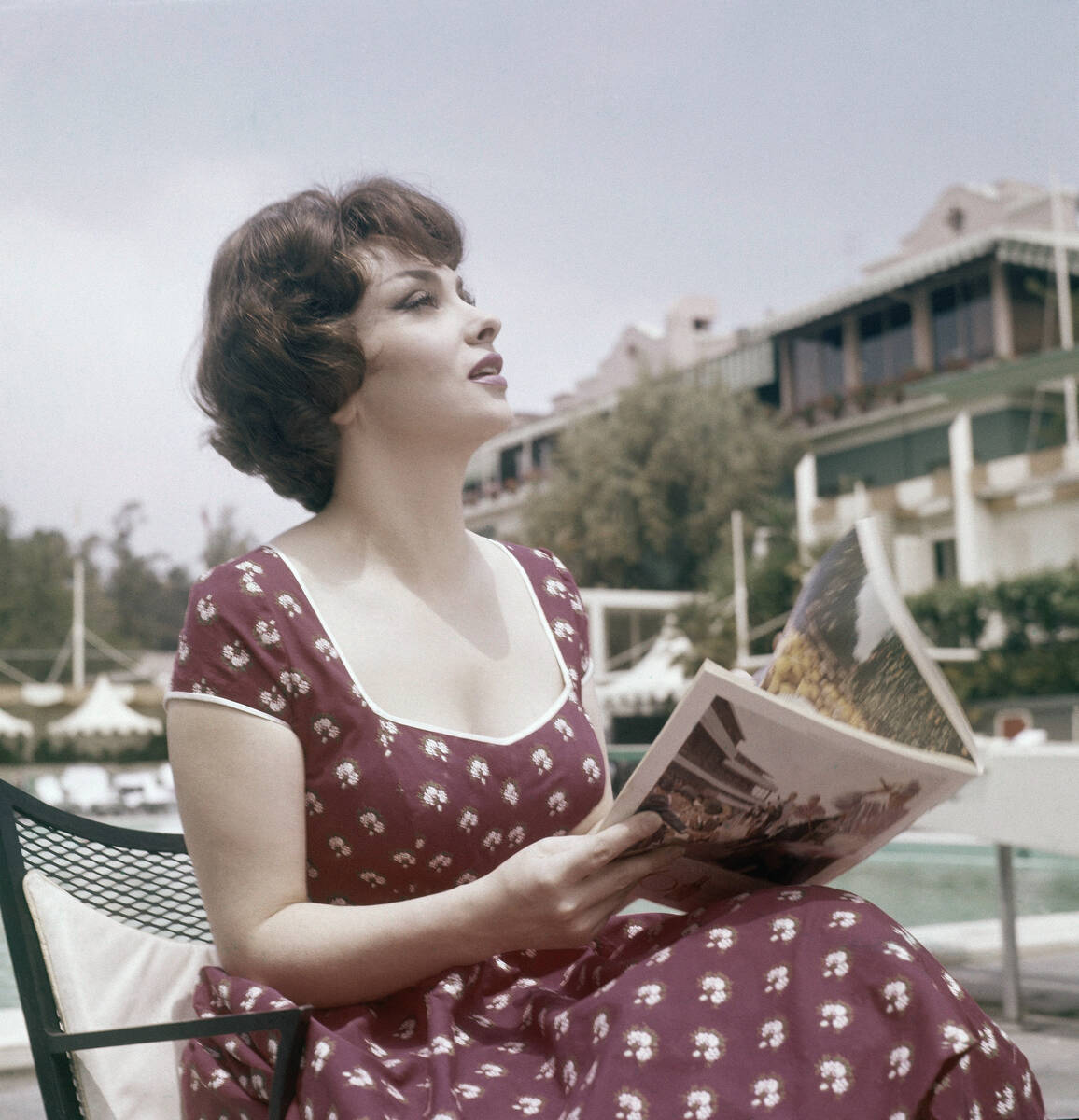 FILE - Actress Gina Lollobrigida reads a magazine as she sits by the pool during her stay at th ...