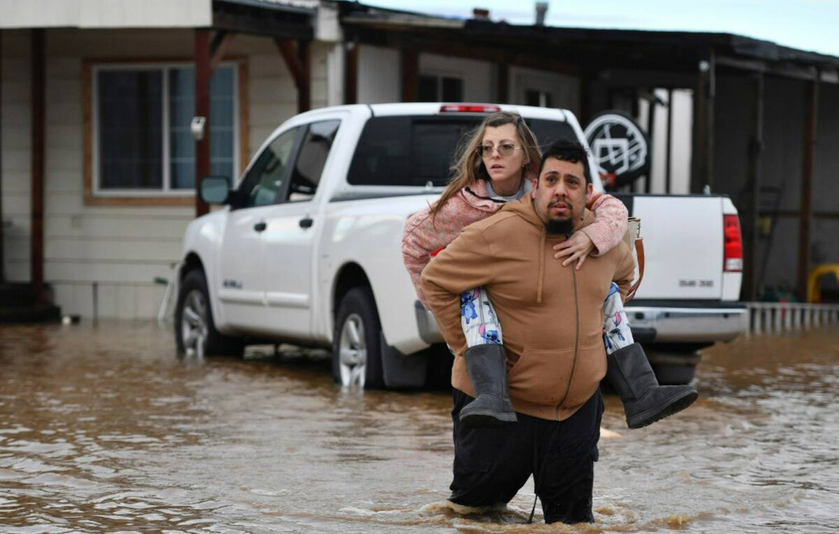 Ryan Orosco, of Brentwood, carries his wife Amanda Orosco, from their flooded home on Bixler Ro ...