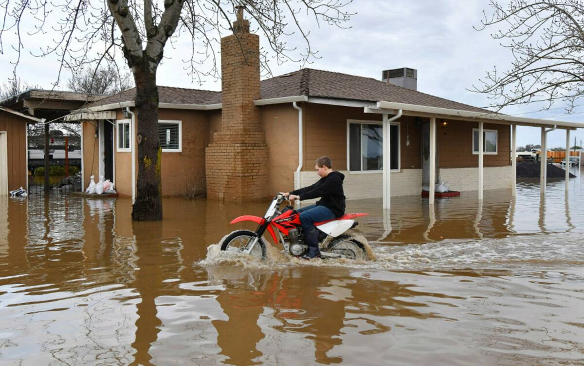 Devan Beard, 13, of Brentwood, rides his off-road motorcycle around his flooded home on Bixler ...