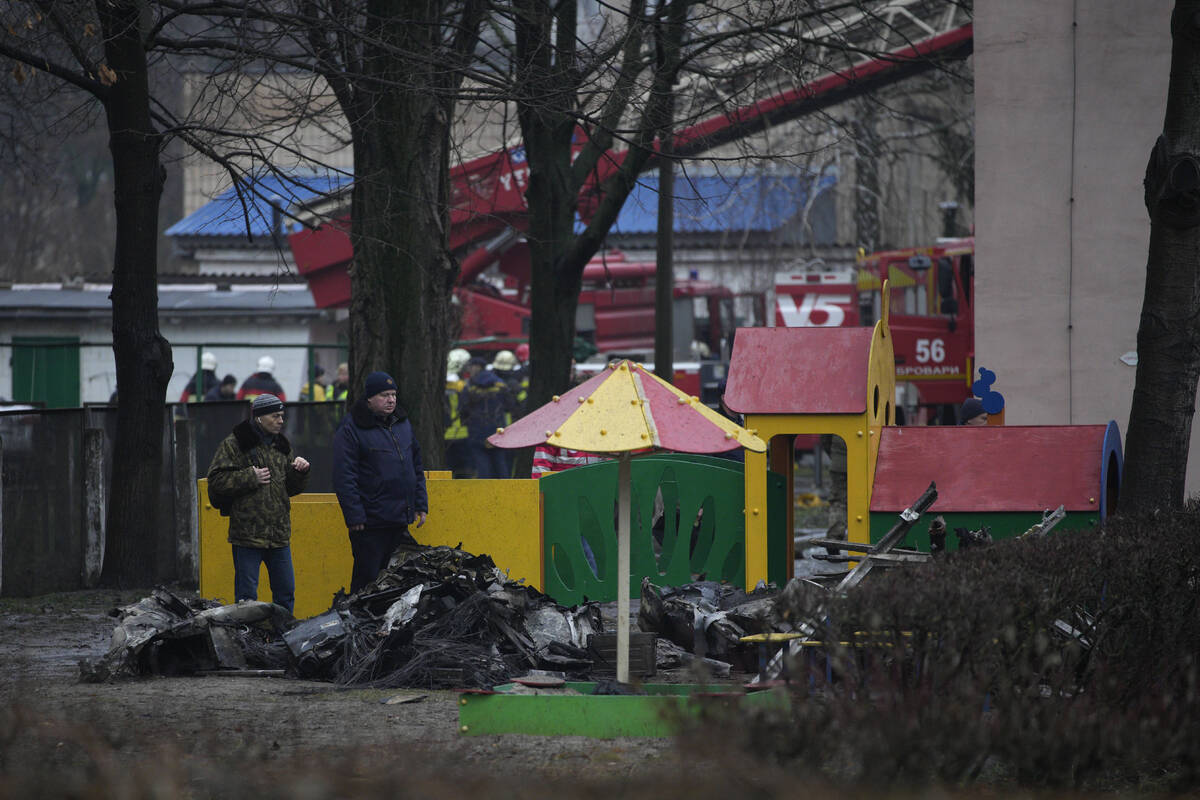 People look at remains of helicopter in a kindergarten at the scene where a helicopter crashed ...