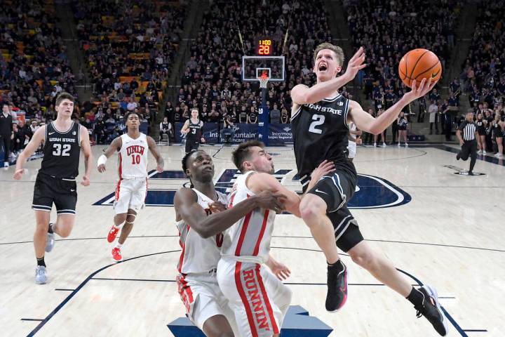 Utah State guard Sean Bairstow (2) drives to the basket as UNLV forward Victor Iwuakor (0) and ...