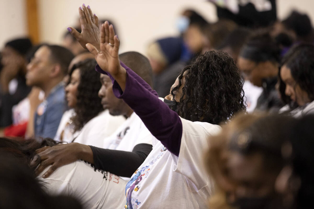 A congregant raises her hands in prayer during a memorial for Ashari Hughes at New Bethel Bapti ...