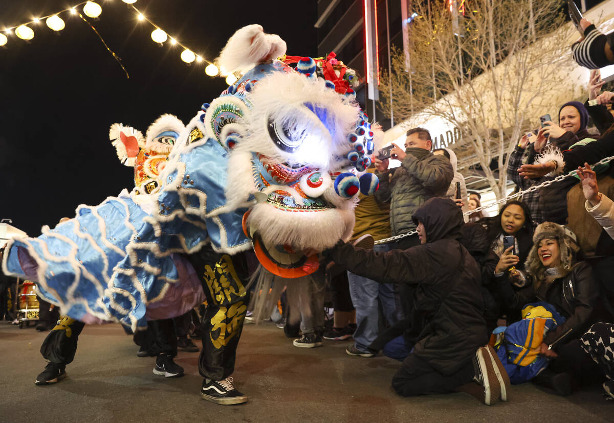 Members of Guan Strong Lion Arts get up close with the crowd during a lion dance during Downtow ...