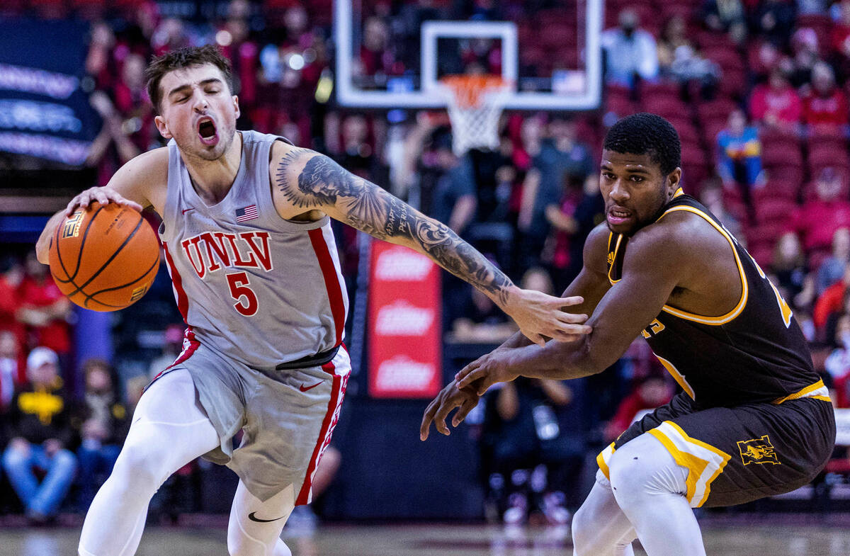 UNLV guard Jordan McCabe (5) pushes past Wyoming guard Ethan Anderson (20) for a drive in the l ...
