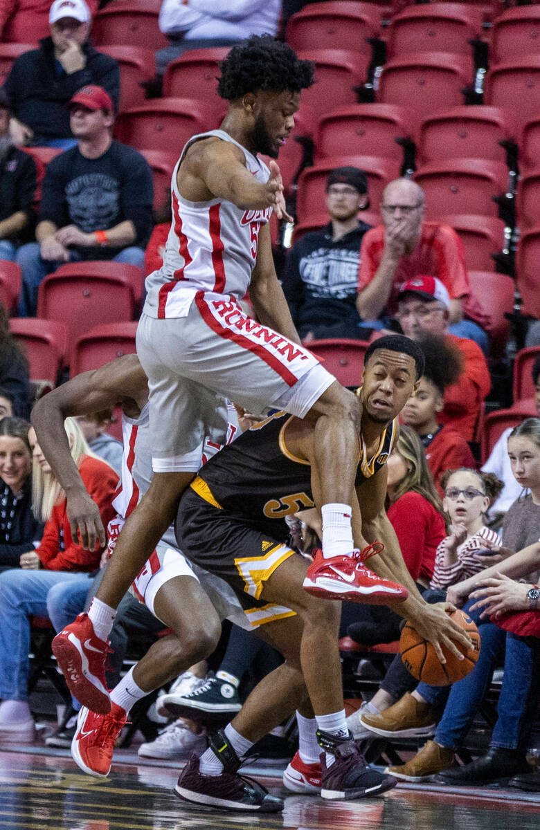 UNLV guard EJ Harkless (55) leaps to defend a pass from Wyoming guard Xavier DuSell (53) who du ...
