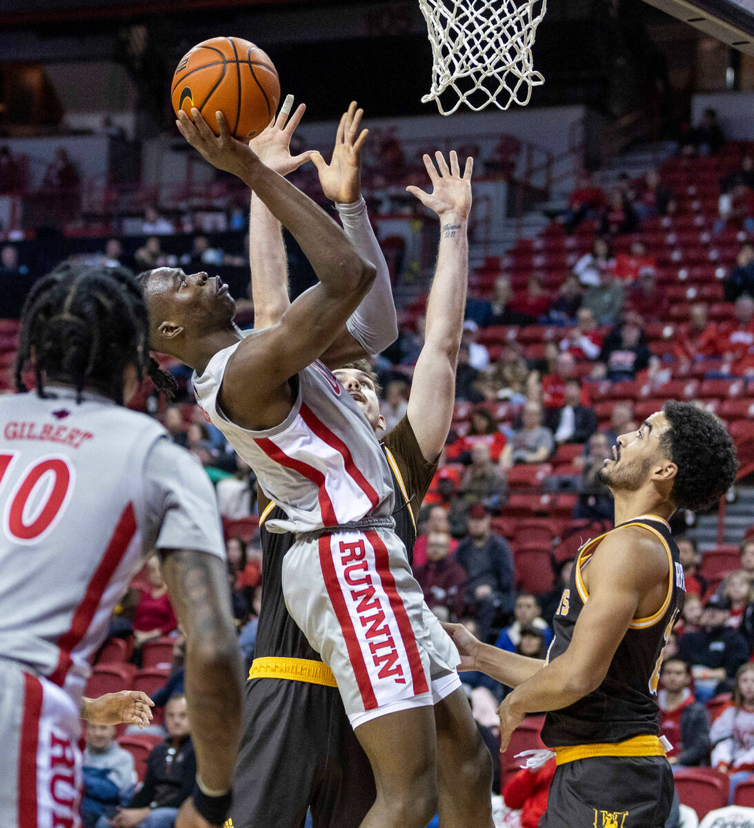 UNLV forward Victor Iwuakor (0) goes back up with a rebound over Wyoming forward Hunter Thompso ...