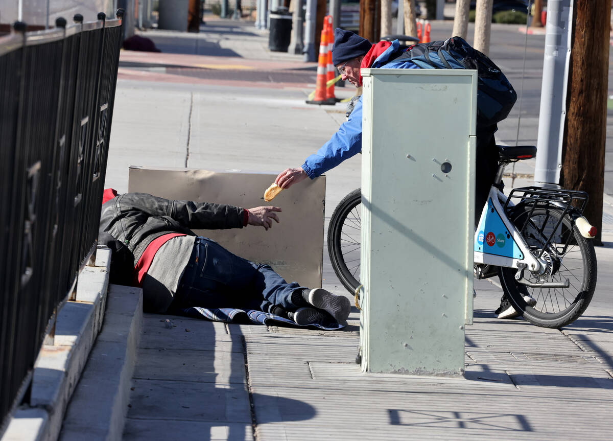Richard Birmingham, right, offers food during his daily bicycle outreach ride in downtown Las V ...