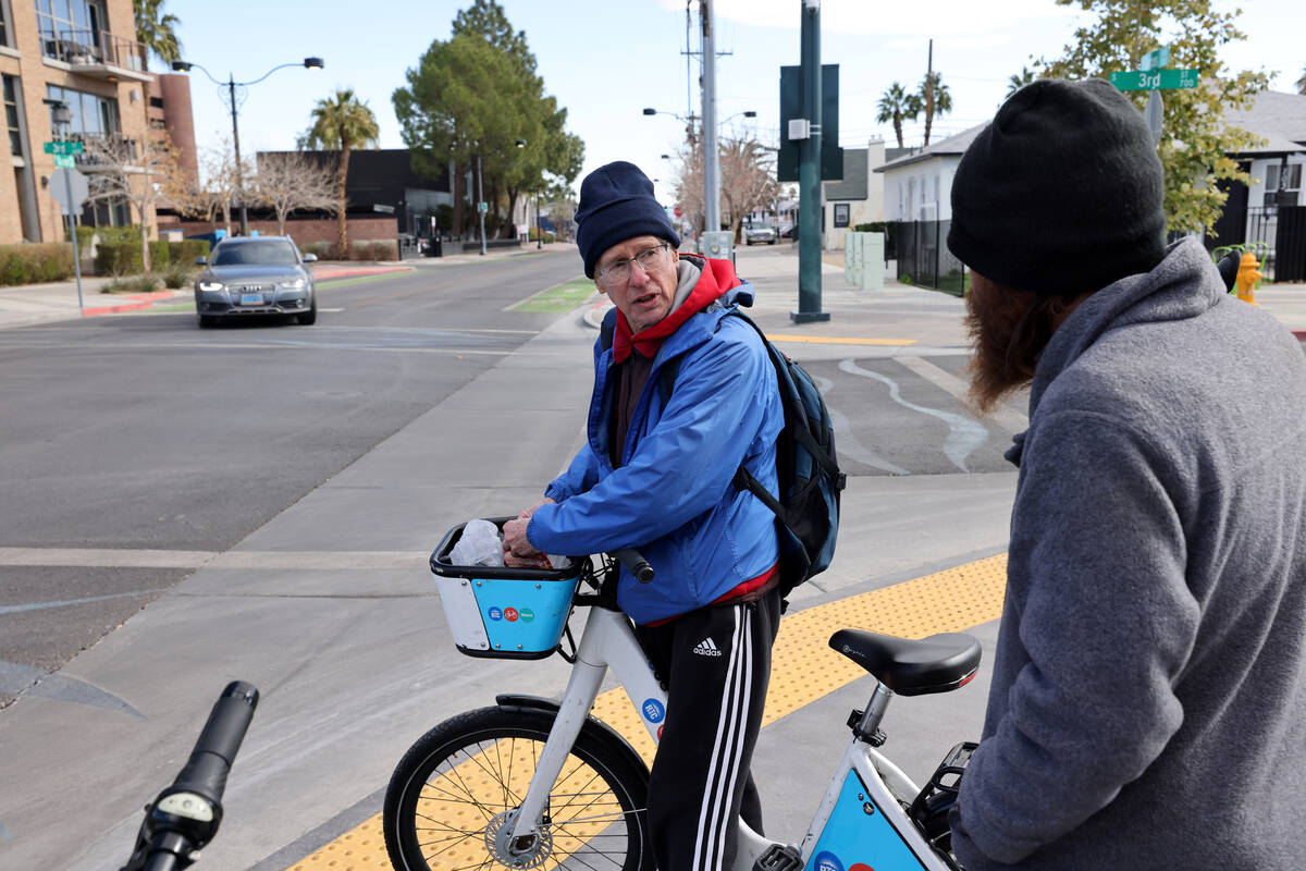Richard Birmingham, left, offers food to Skyler Bryant, 43, during his daily bicycle outreach r ...