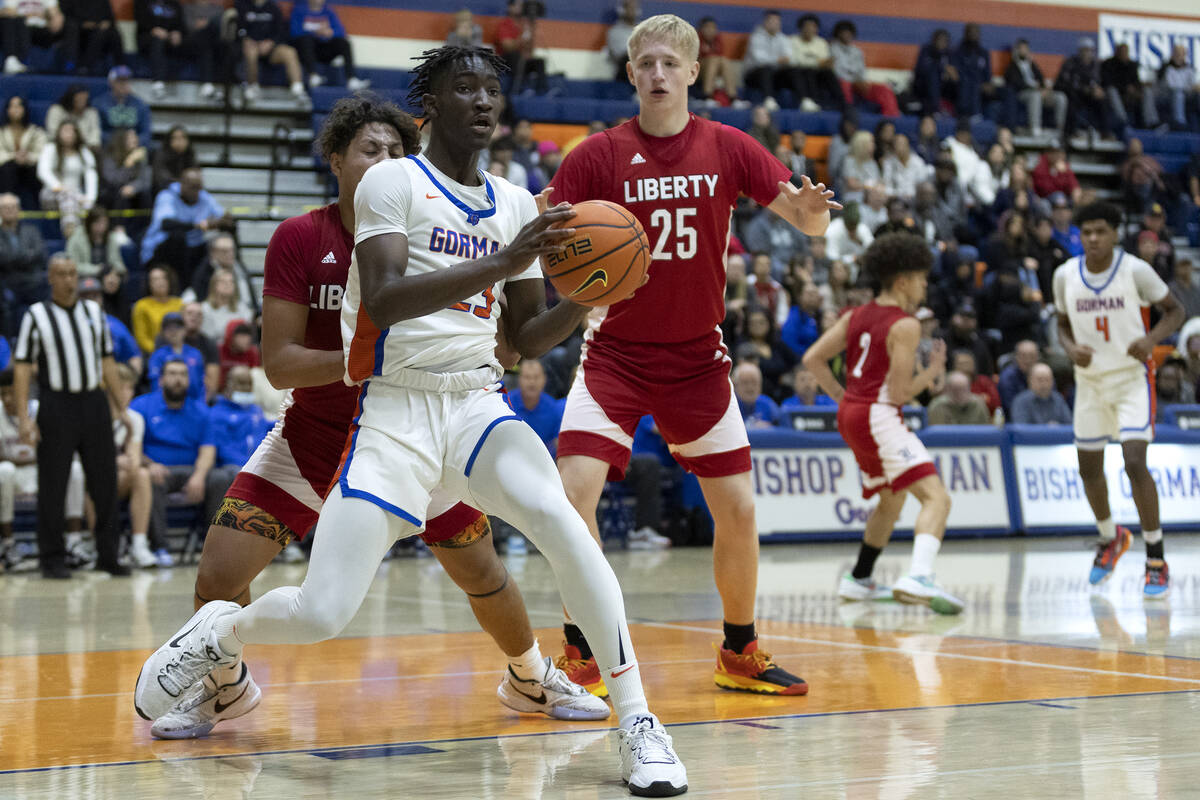 Bishop Gorman’s Chris Nwuli (23) looks to pass while guarded by Liberty’s Andre P ...