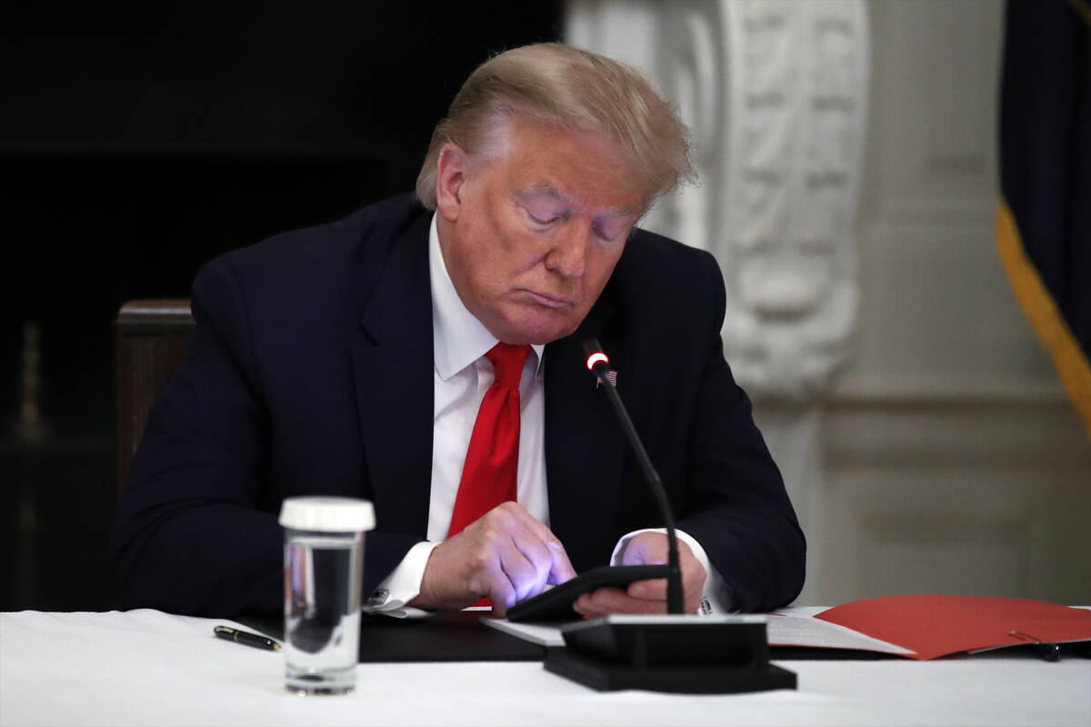 In this Thursday, June 18, 2020, file photo, President Donald Trump looks at his phone during a ...