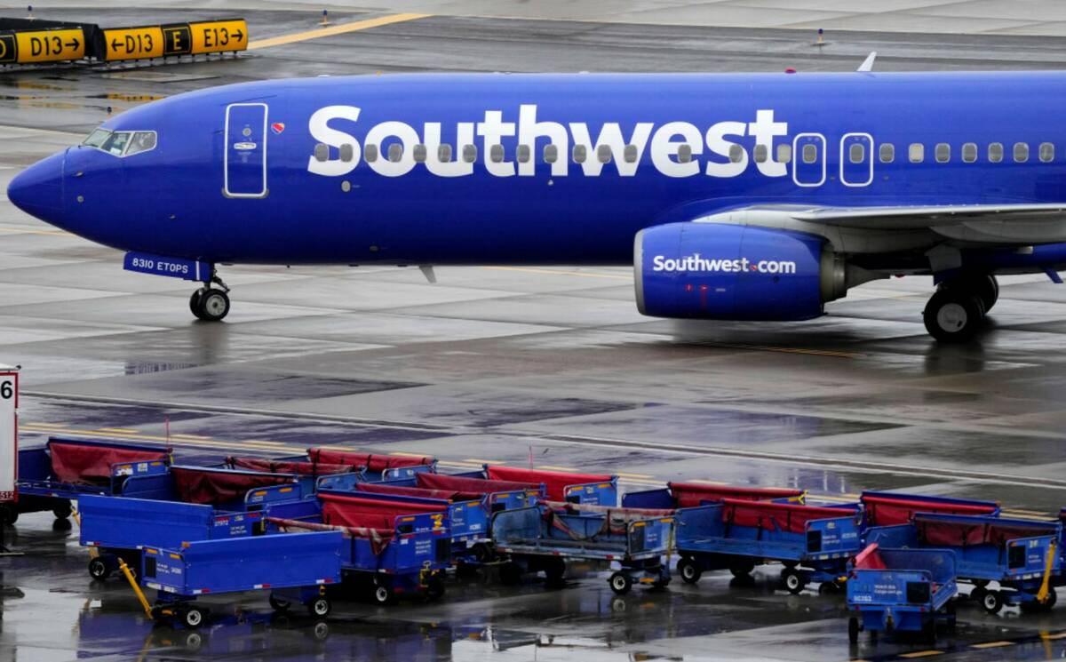 A Southwest Airlines jet passes unused luggage carts as it arrives, Dec. 28, 2022, at Sky Harbo ...