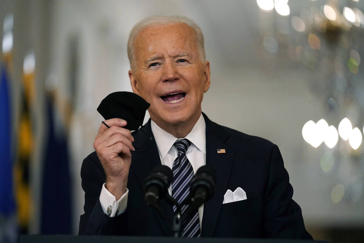 FILE - In this March 11, 2021, file photo, President Joe Biden holds up his face mask as he spe ...