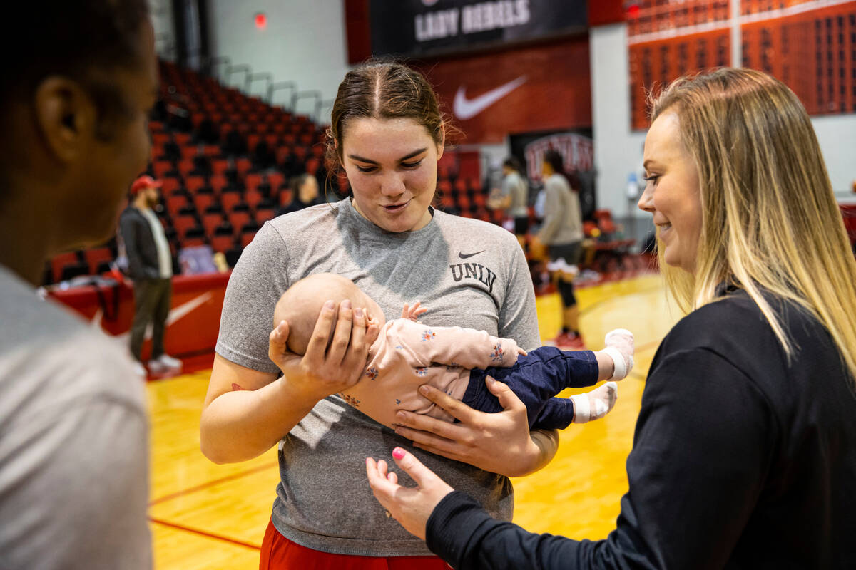 UNLV center Erica Collins, left, holds Ellie Cunningham, the newborn baby of UNLV Lady Rebels h ...