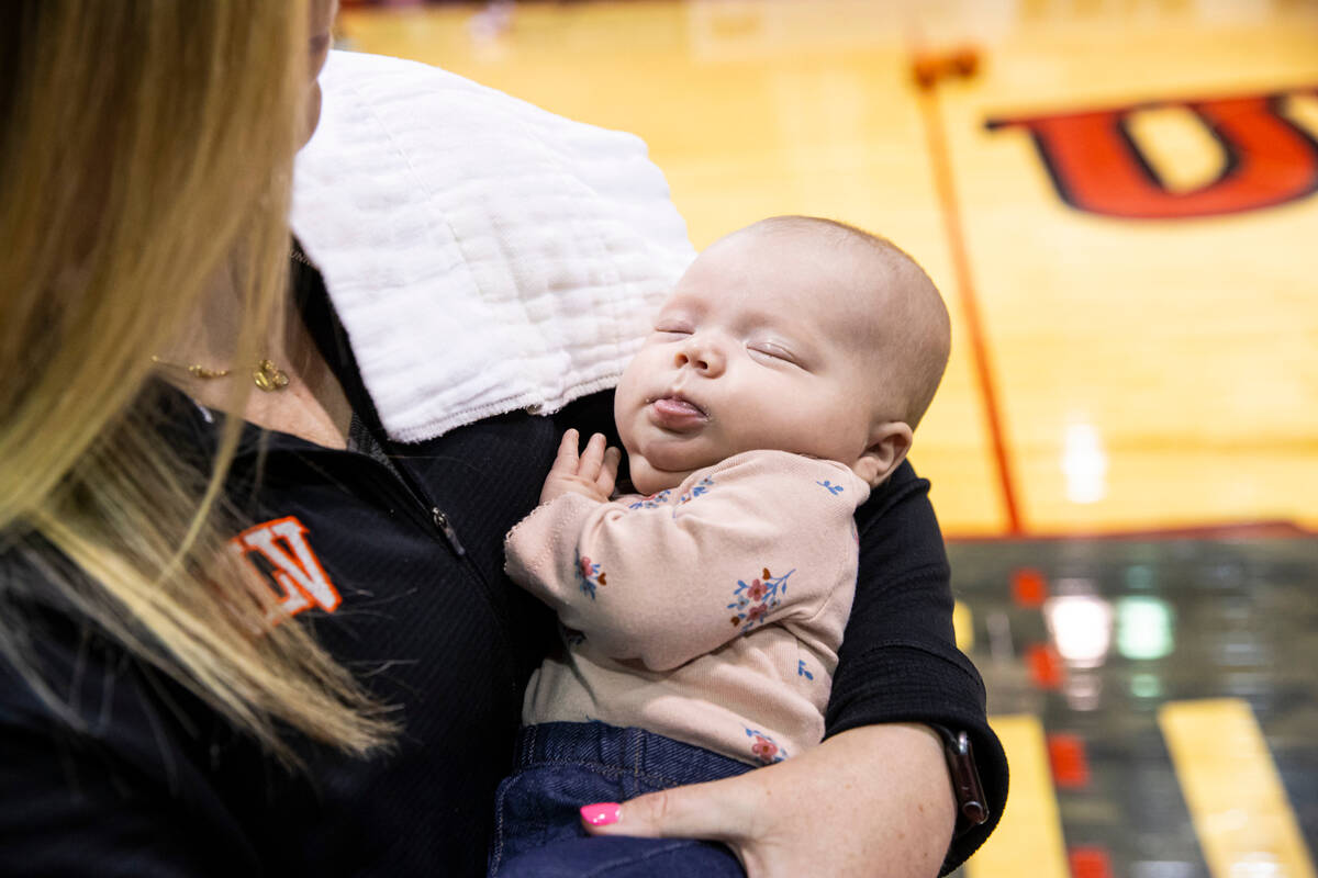 UNLV Lady Rebels head coach Lindy La Rocque holds her baby, Ellie Cunningham, while leading bas ...