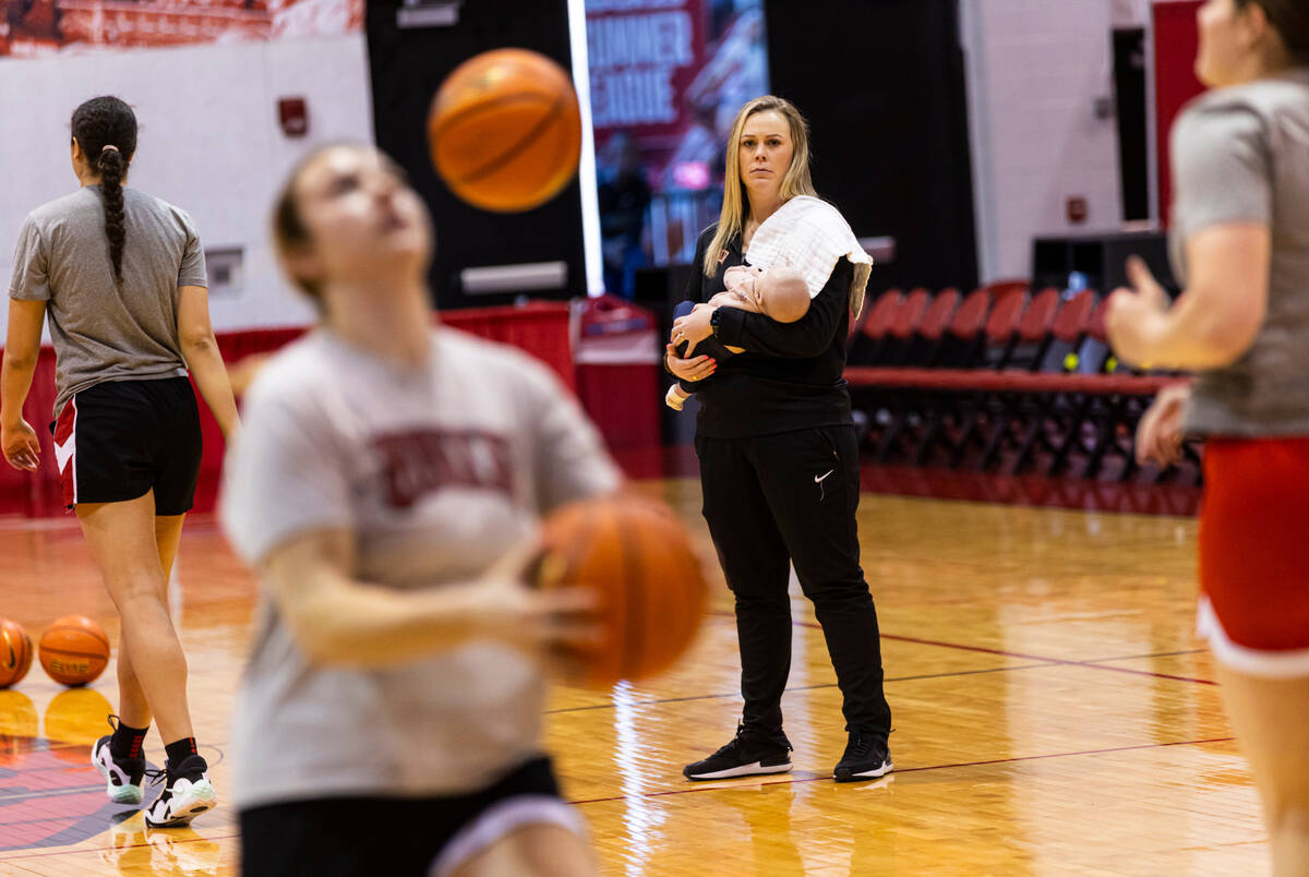UNLV Lady Rebels head coach Lindy La Rocque holds her baby, Ellie Cunningham, while leading bas ...