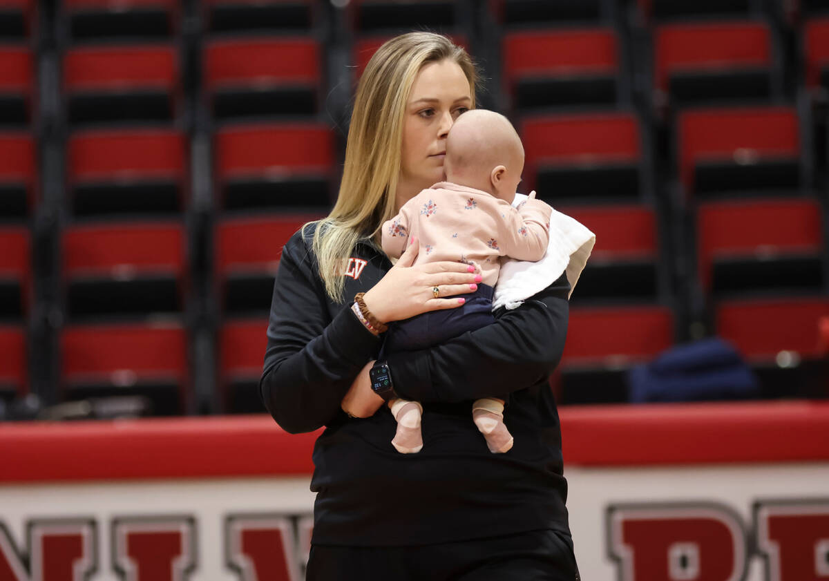 UNLV Lady Rebels head coach Lindy La Rocque holds her baby, Ellie Cunningham, while leading bas ...
