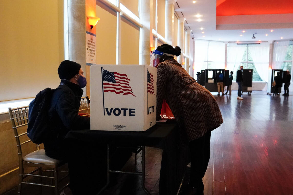 FILE - In this Nov. 3, 2020, file photo, a poll worker talks to a voter before they vote on a p ...