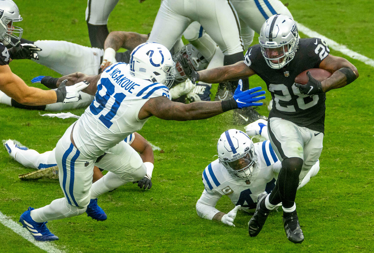 Raiders running back Josh Jacobs (28) fights to turn the corner on Indianapolis Colts defensive ...