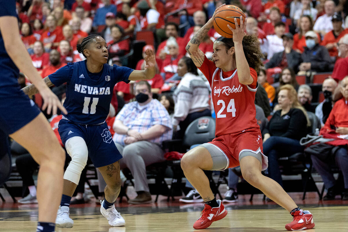 UNLV Lady Rebels guard Essence Booker (24) pivots with the ball while Nevada Wolf Pack guard Vi ...