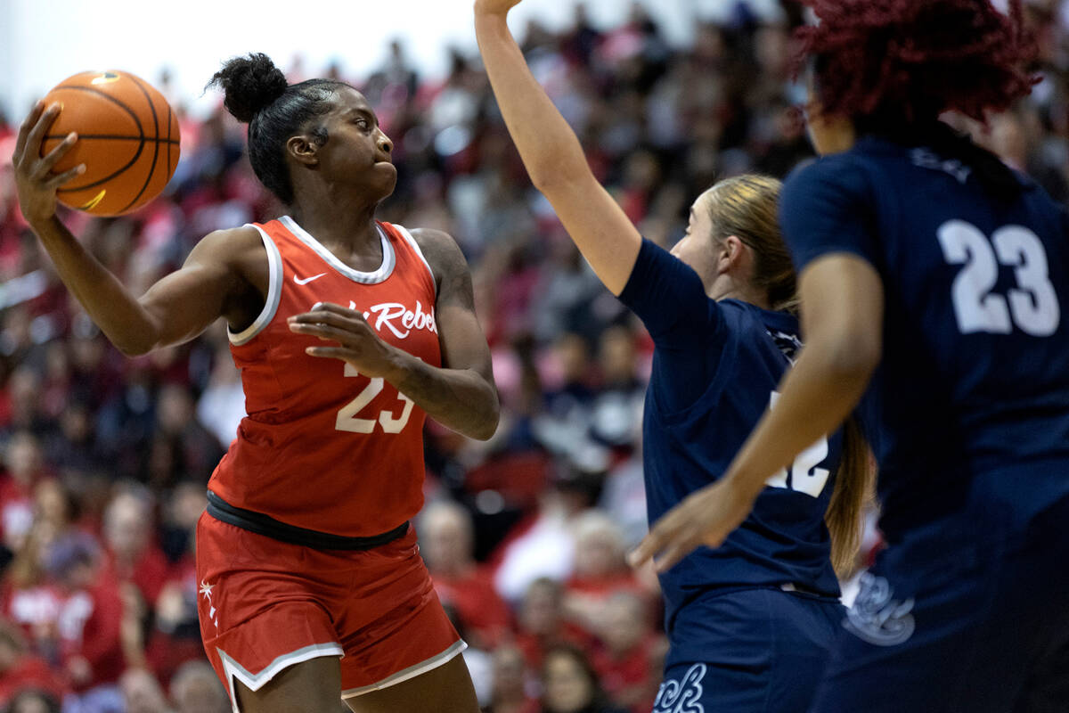 UNLV Lady Rebels center Desi-Rae Young (23) looks to pass while Nevada Wolf Pack guard Alyssa J ...
