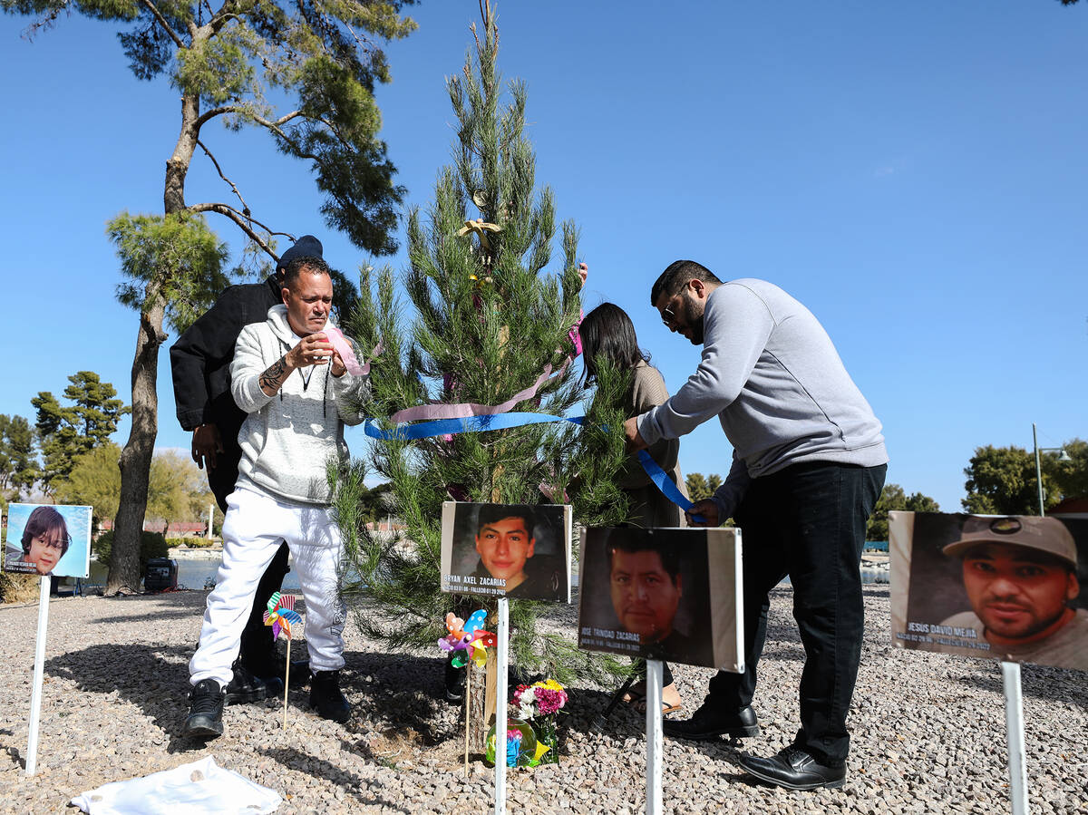 Jesus Mejia-Santana, left, along with family friend Juan Perez, right, decorates a tree planted ...