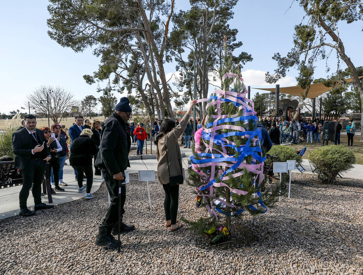 Spectators look on as family and friends decorate a tree to honor the seven members of a family ...