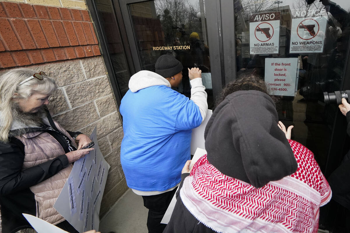 A group of demonstrators knock on a locked entrance as they protest outside a police precinct i ...