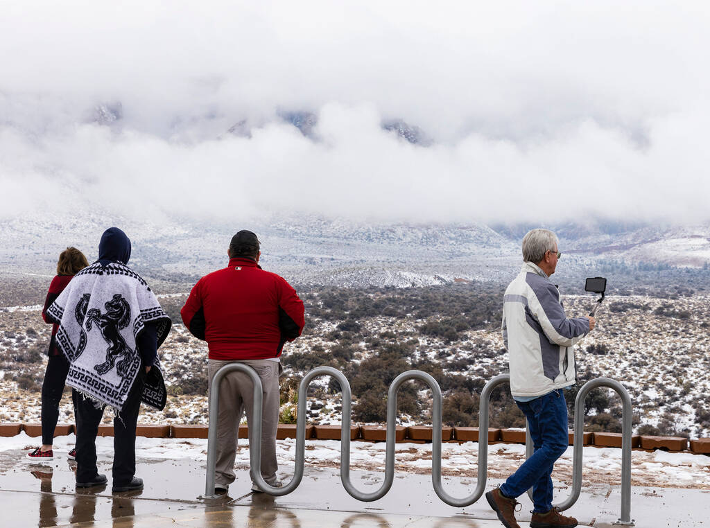 Tourists stop at the Red Rock Canyon overlook to admire the view of snow-capped mountains on Mo ...