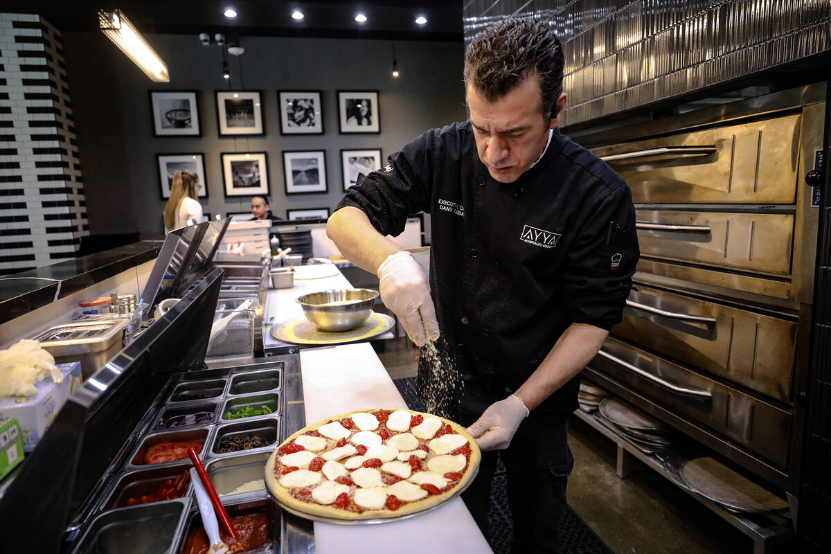 Executive chef Dany Chebat sprinkles Parmesan cheese on the parma pizza pie at Crust & Roux in ...