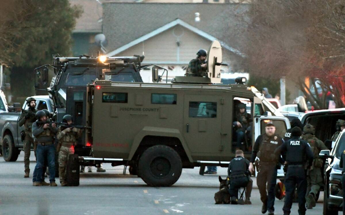 Law enforcement officers aim their weapons at a home during a standoff in Grants Pass, Ore., on ...