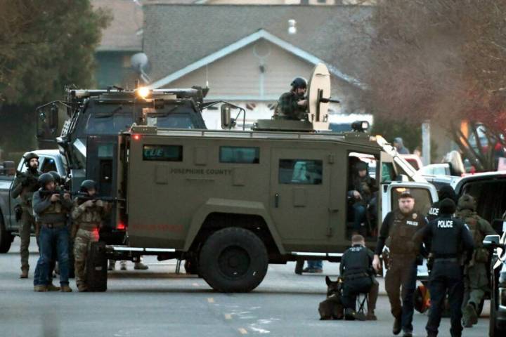 Law enforcement officers aim their weapons at a home during a standoff in Grants Pass, Ore., on ...