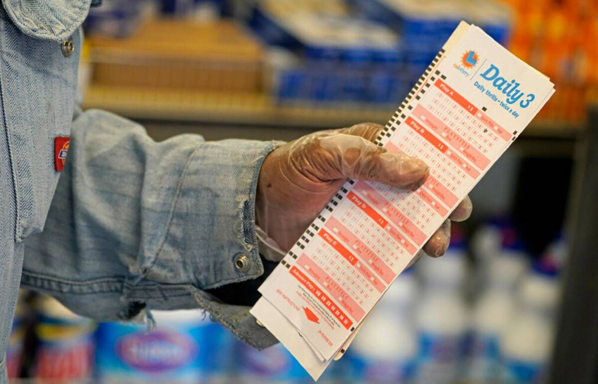 Philip Smith wears gloves as he lines up to purchase lottery tickets for the Monday, Oct. 31, d ...