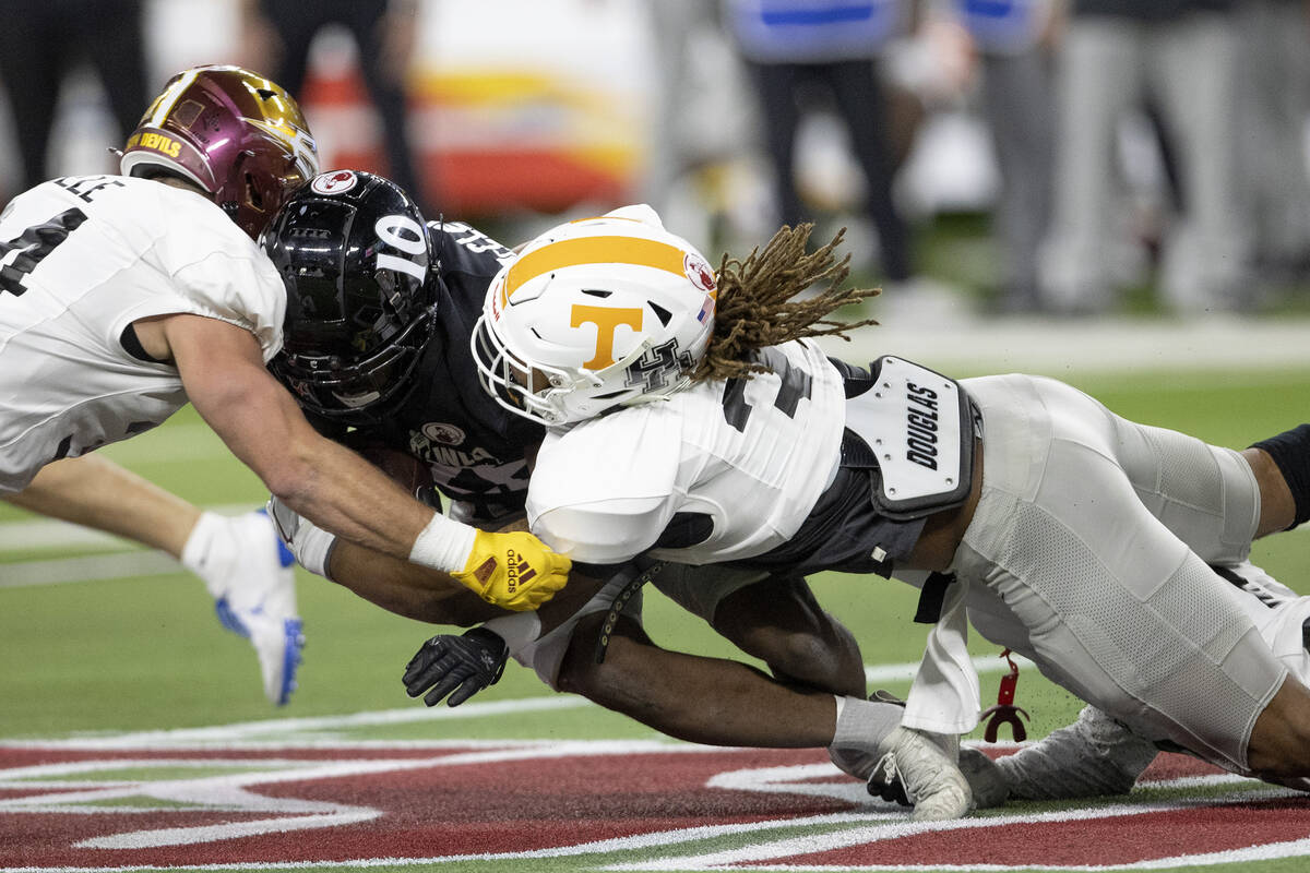West running back Charles McClelland, center, of Cincinnati, is tackled by East linebackers Kyl ...