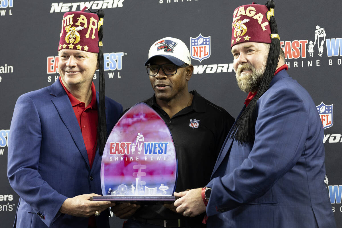 West head coach Troy Brown of the New England Patriots is presented a trophy by the Shriners af ...