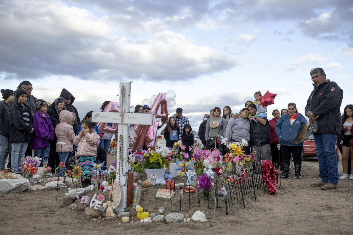 Loved ones of Anna Scott, a member of the Pyramid Lake Paiute Tribe, pray over her grave during ...