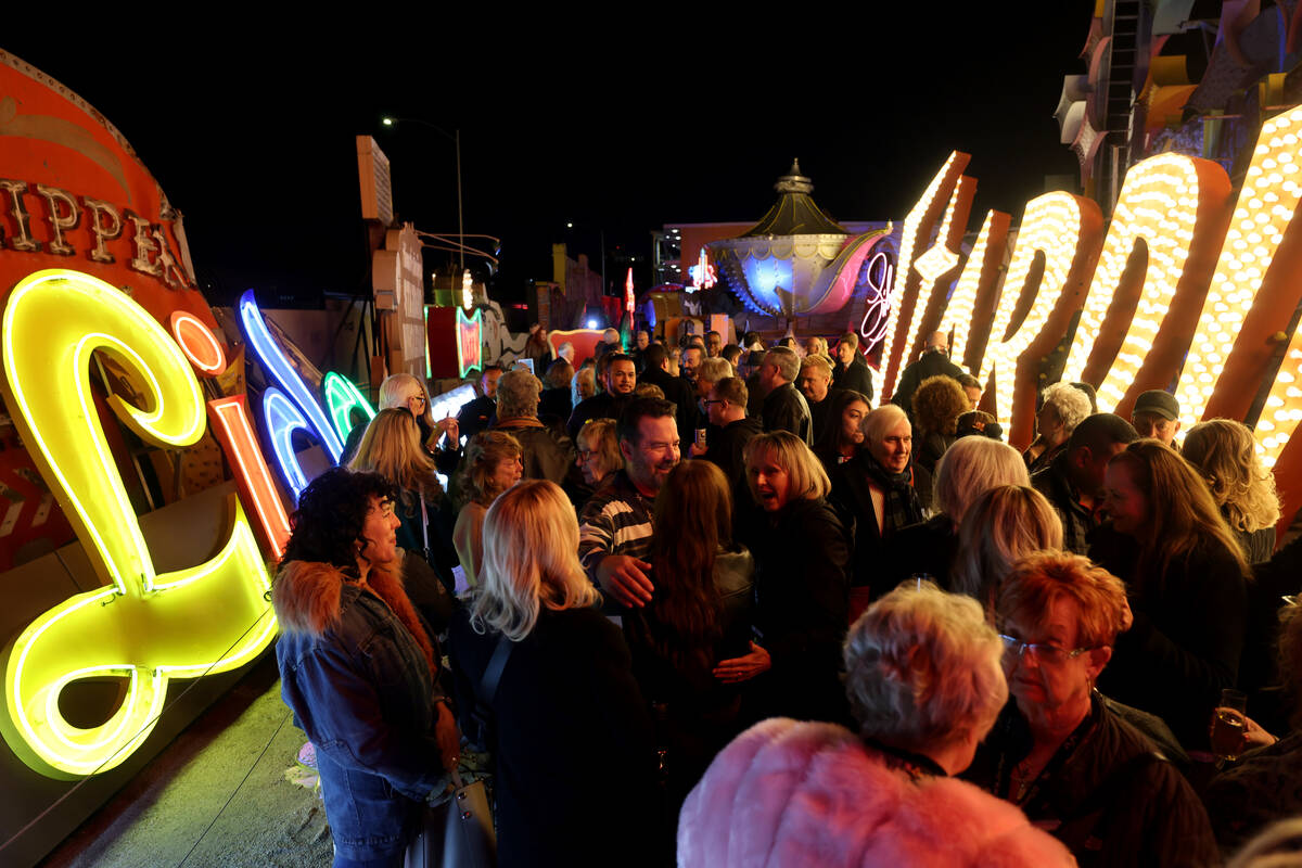 Museum members and Lido de Paris cast members and workers mingle with the newly lit sign during ...