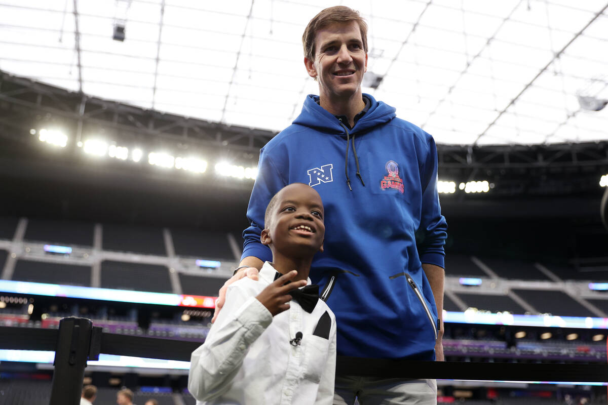 Jeremiah Fennell, 10, left, poses for a photo with former NFL quarterback Eli Manning during a ...