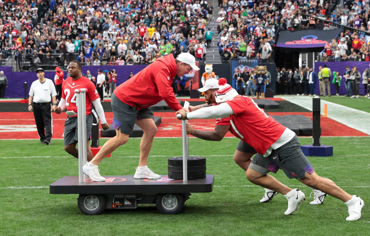 AFC head coach Peyton Manning is pushed by players competing in the gridiron gauntlet event dur ...