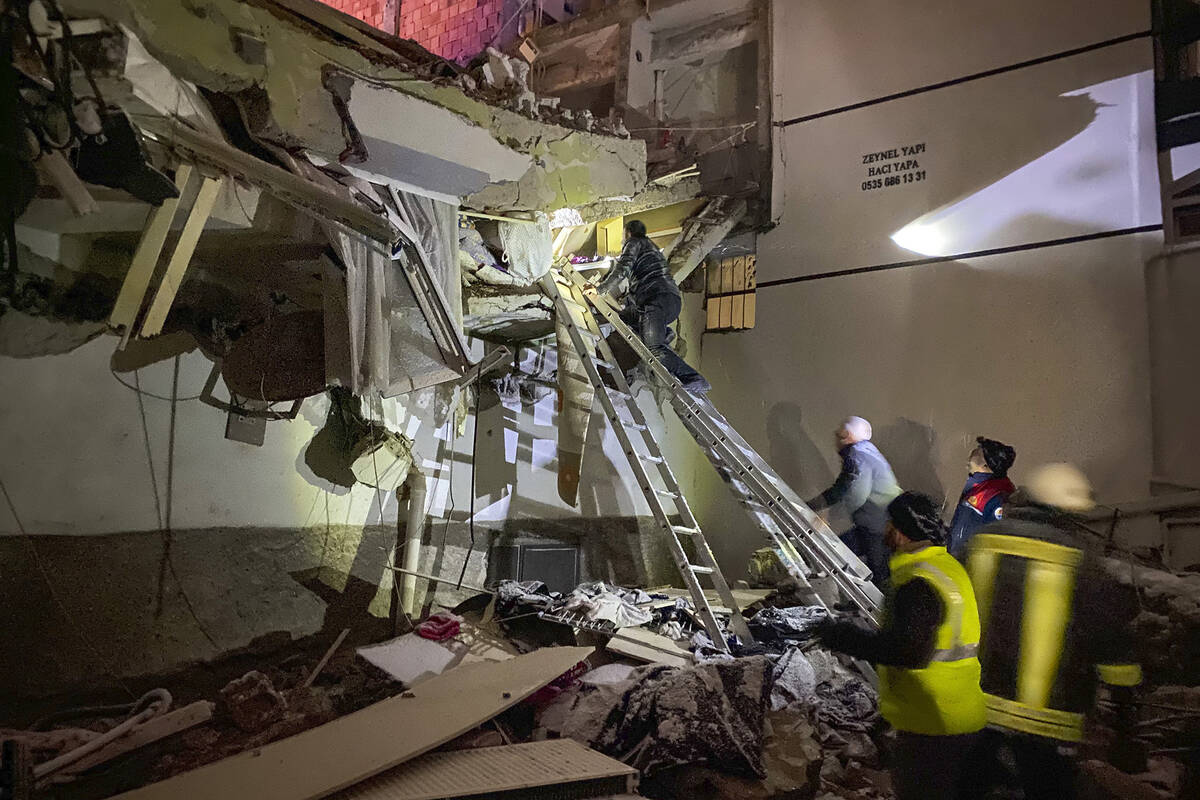 Rescue teams try to reach trapped residents inside collapsed buildings in Adana, Turkey, Monday ...